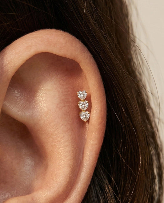 Close-up of an ear wearing two diamond stud earrings with a neutral background